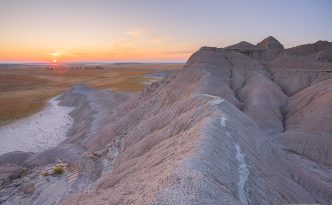 I watch as the sun rises over the western Nebraska plains from atop a ridge in Toadstool Geologic Park.