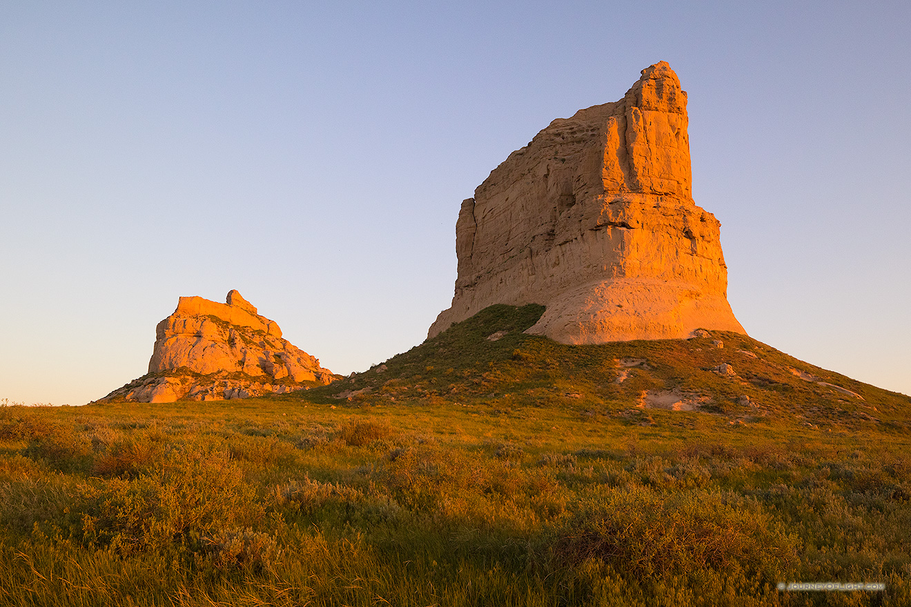 Jailhouse and Courthouse Rock both glow red with the first light at sunrise.