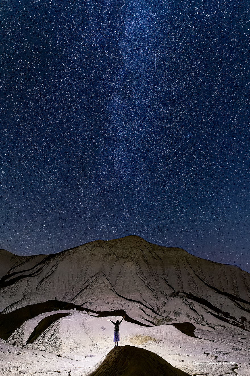 The badlands of Toadstool Geologic Park are illuminated by a single flashlight while the stars above shine brightly.