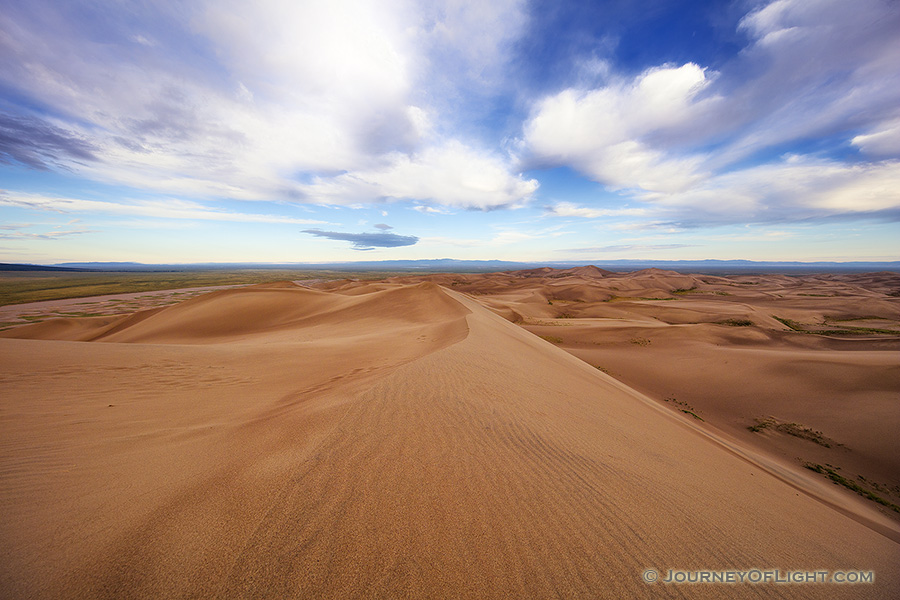 At Great Sand Dunes National Park and Preserve, dunes flow into the west as white clouds float high above. - Great Sand Dunes NP Photography