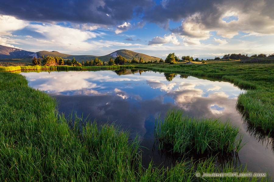 An idyllic mountain scene on the tundra of Rocky Mountain National Park.  A small tarn reflects the beautiful sky and the mountains in the distance. - Colorado Photography