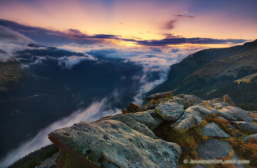 As clouds gather in the valley below, from the tundra of Rocky Mountain National Park, the sun sets behind the mountains of Colorado, the last rays burst forth with orange and yellow before dimming altogether. - Rocky Mountain NP Photography