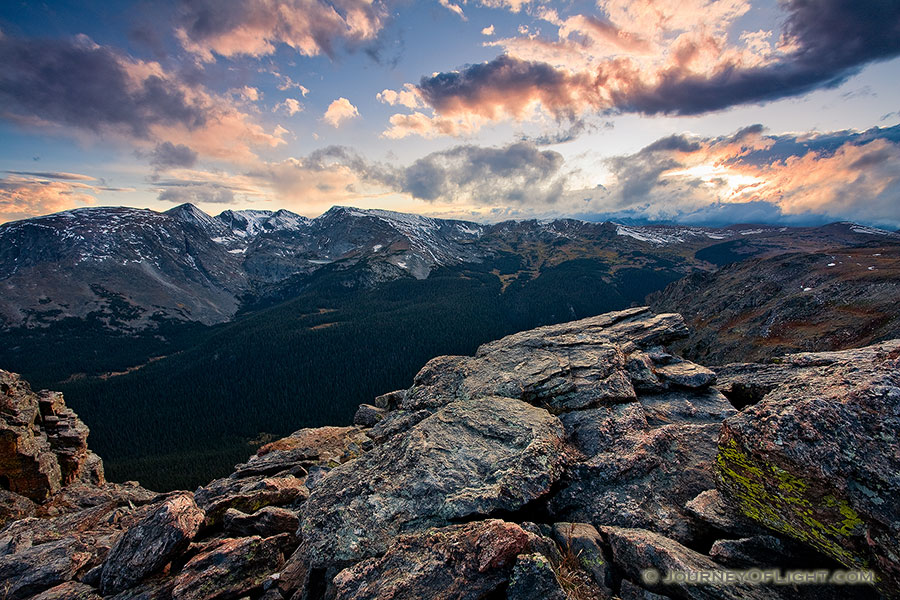 The setting sun streams through the clouds, illuminating the peaks of Rocky Mountain National Park and the valley below. - Colorado Photography