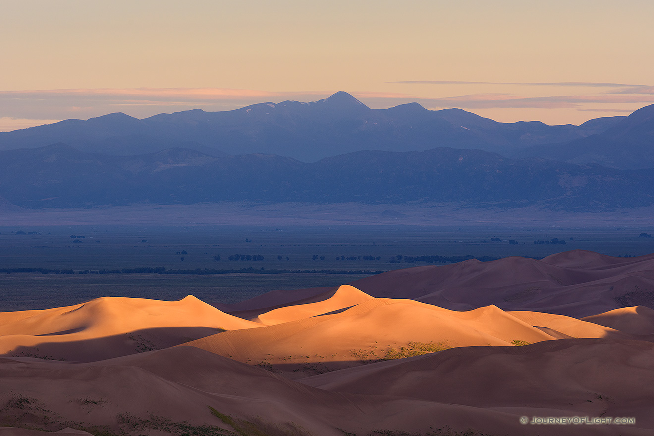 Light graces the tops of the Sand Dunes in the distance as the sun peaks over the Sangre De Cristo range. - Great Sand Dunes NP Picture