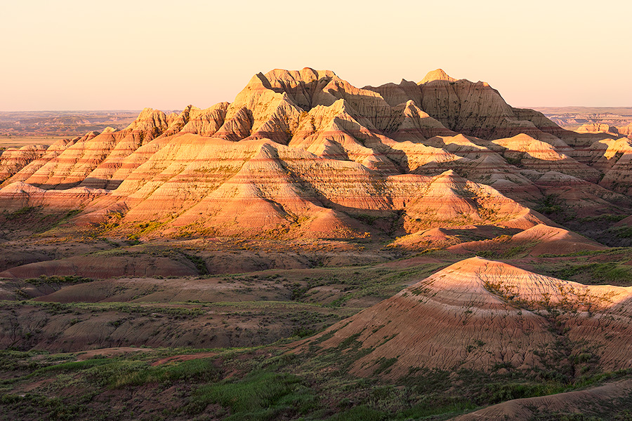 Light from the recently risen sun illuminates the Badlands in South Dakota with a warm orange hue. - South Dakota Photography
