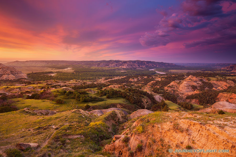 Above a bend in the Little Missouri River in the North Unit of Theodore Roosevelt National Park, clouds glow purple and orange as the sun just begins to rise above the horizon. - North Dakota Photography