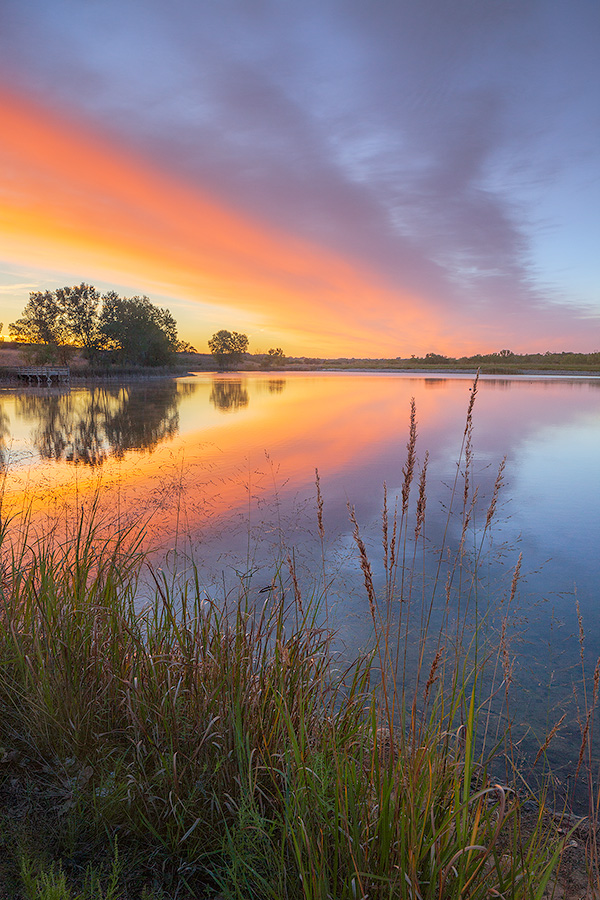 A landscape photograph of a sunrise reflected in a lake at Mahoney State Park, Nebraska. - Nebraska Photography