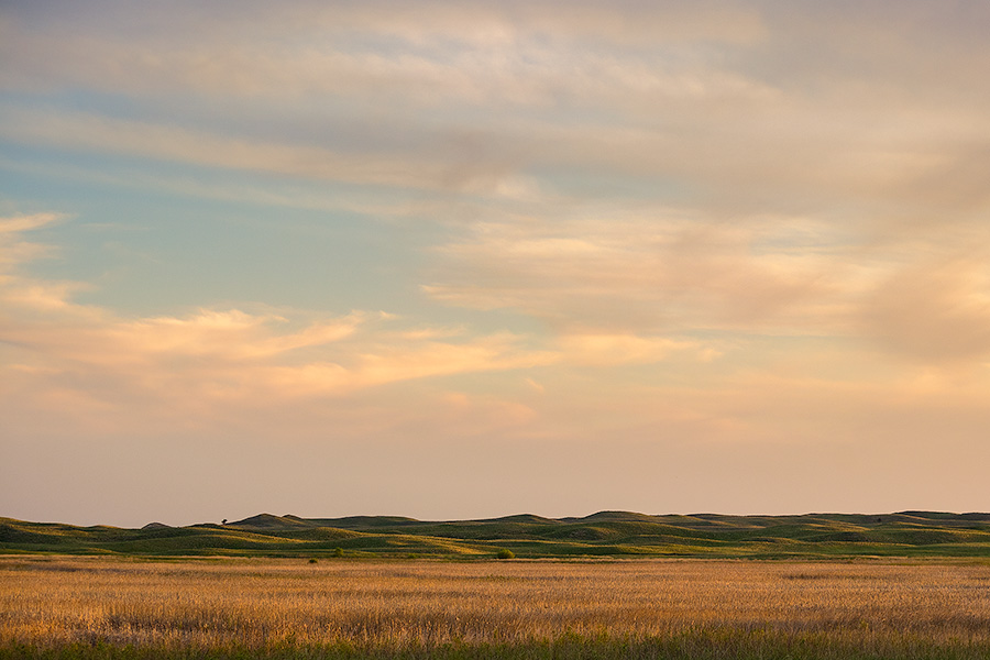 The last light of sunset skims across the Nebraska Sandhills and casts a warm glow on the clouds above. - Nebraska Photography