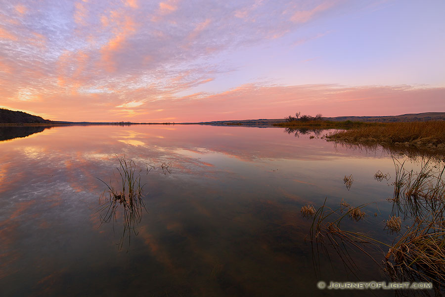 On a calm and quiet evening in early November at Niobrara State Park, just prior to sunset, I hiked down to near the confluence of the Missouri River and Niobrara Rivers and took in the scene.  The last of the light of the sun illuminated the clouds and the still Missouri reflected the scene sandwiched between the hills of Nebraska and South Dakota. - Nebraska Photography