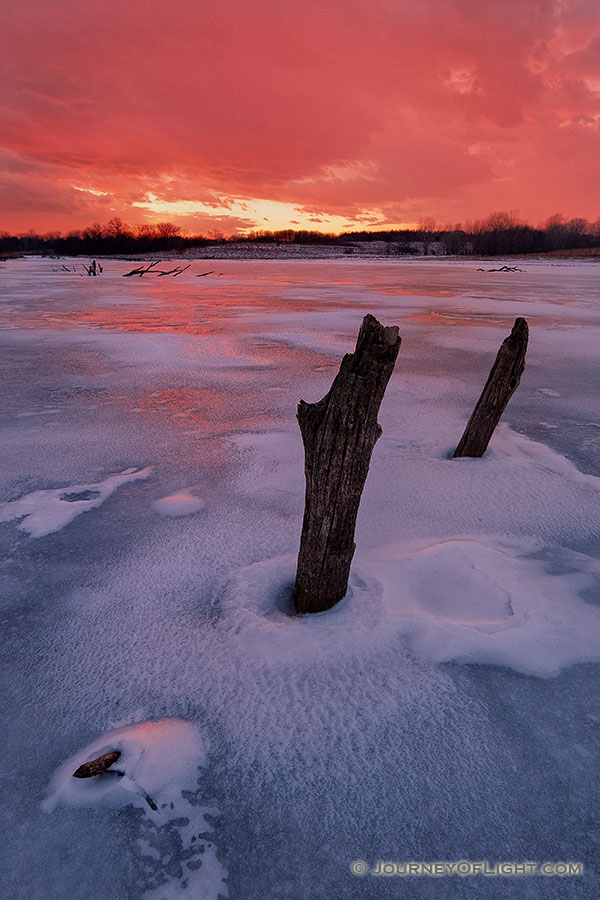 On a chilly February evening the setting sun illuminates the clouds in the western sky with a dazzling crimson color. - Nebraska Photography