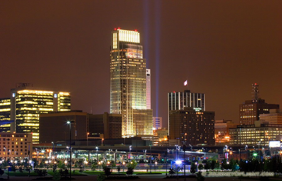 On September 11, 2006 Omaha, Nebraska paid tribute to the victims of 9/11 by hanging 2 large United States flags on the Woodmen tower and by shining two large lights into the sky. - Omaha Photography