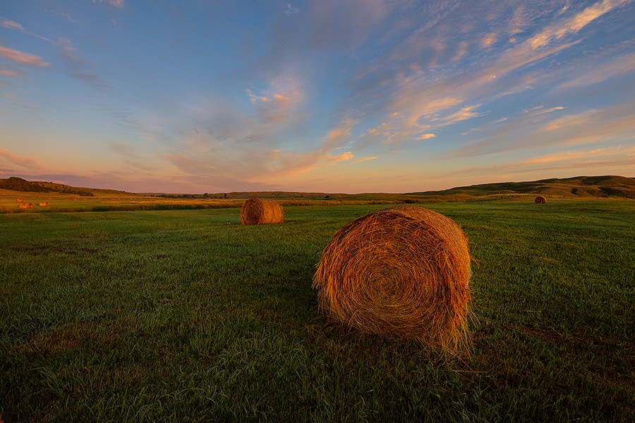 A scenic landscape photograph of hay bales and a beautiful glow in the sandhills of Nebraska. - Nebraska Photography