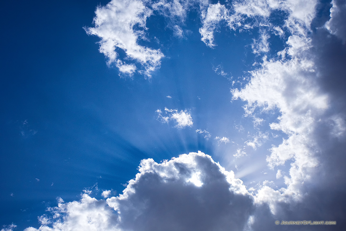 Sunbeams radiate from behind a cloud in the deep azure sky at Valentine National Wildlife Refuge, Nebraska. - Valentine Picture