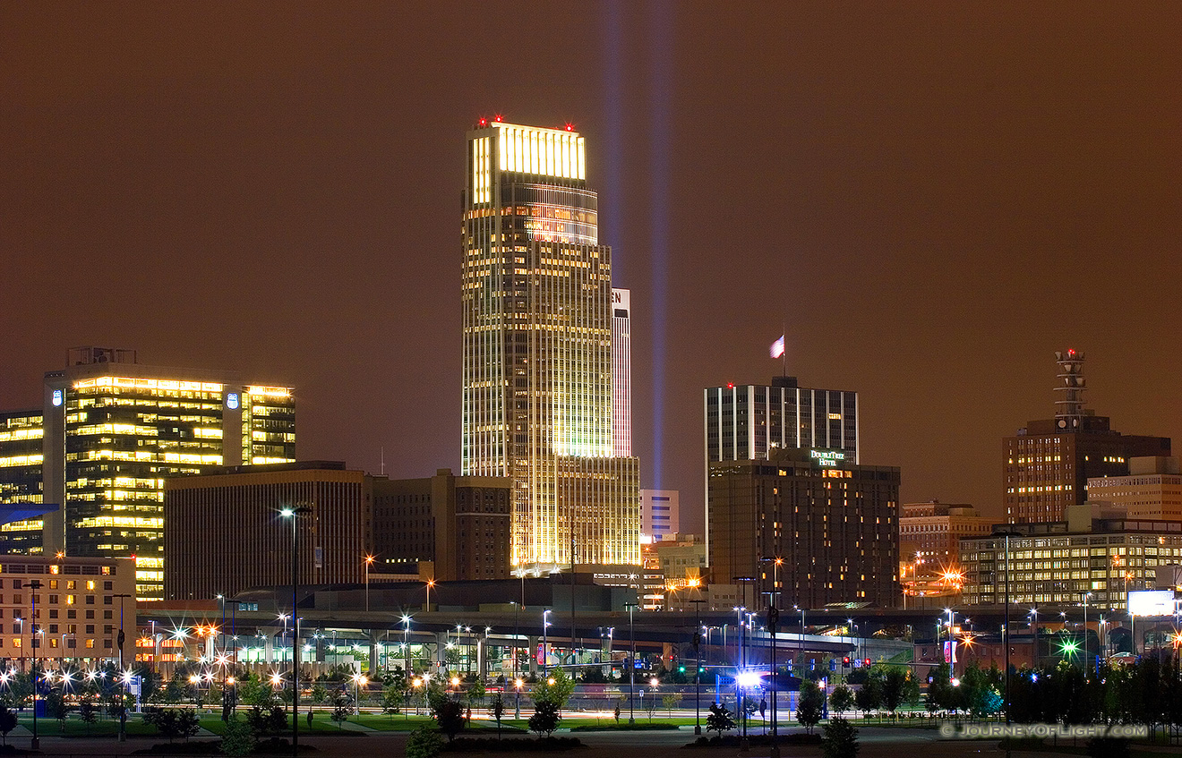 On September 11, 2006 Omaha, Nebraska paid tribute to the victims of 9/11 by hanging 2 large United States flags on the Woodmen tower and by shining two large lights into the sky. - Omaha Picture