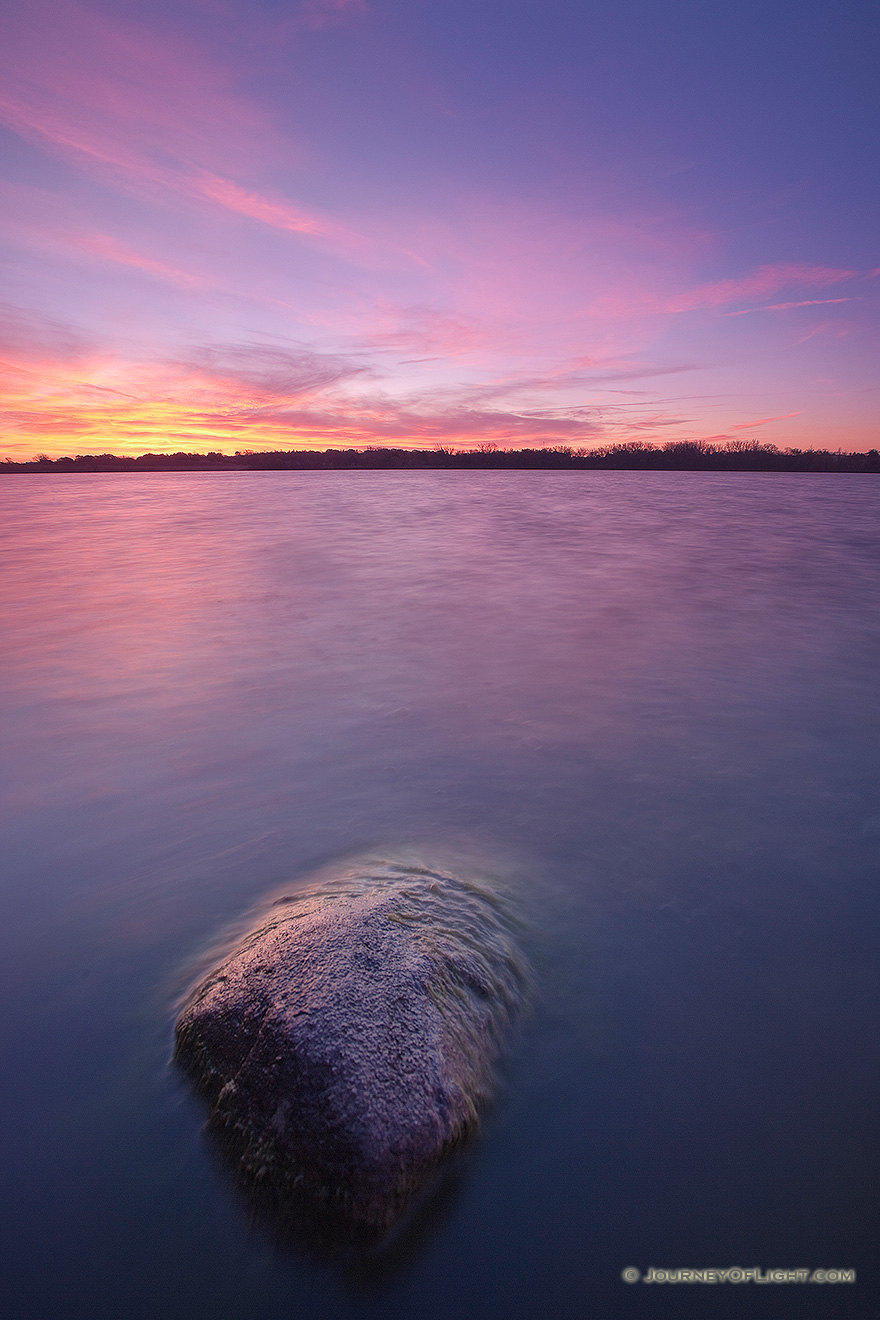 On a late Autumn morning, clouds on the horizon of Stagecoach Lake in Lancaster County, Nebraska are illuminated with bright yellows and reds. - Nebraska Picture