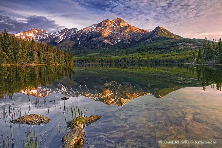 Morning light bathes Pyramid mountain in Jasper National Park.The scene is nearly perfect reflected in the still waters of Pyramid Lake. - Jasper Photography