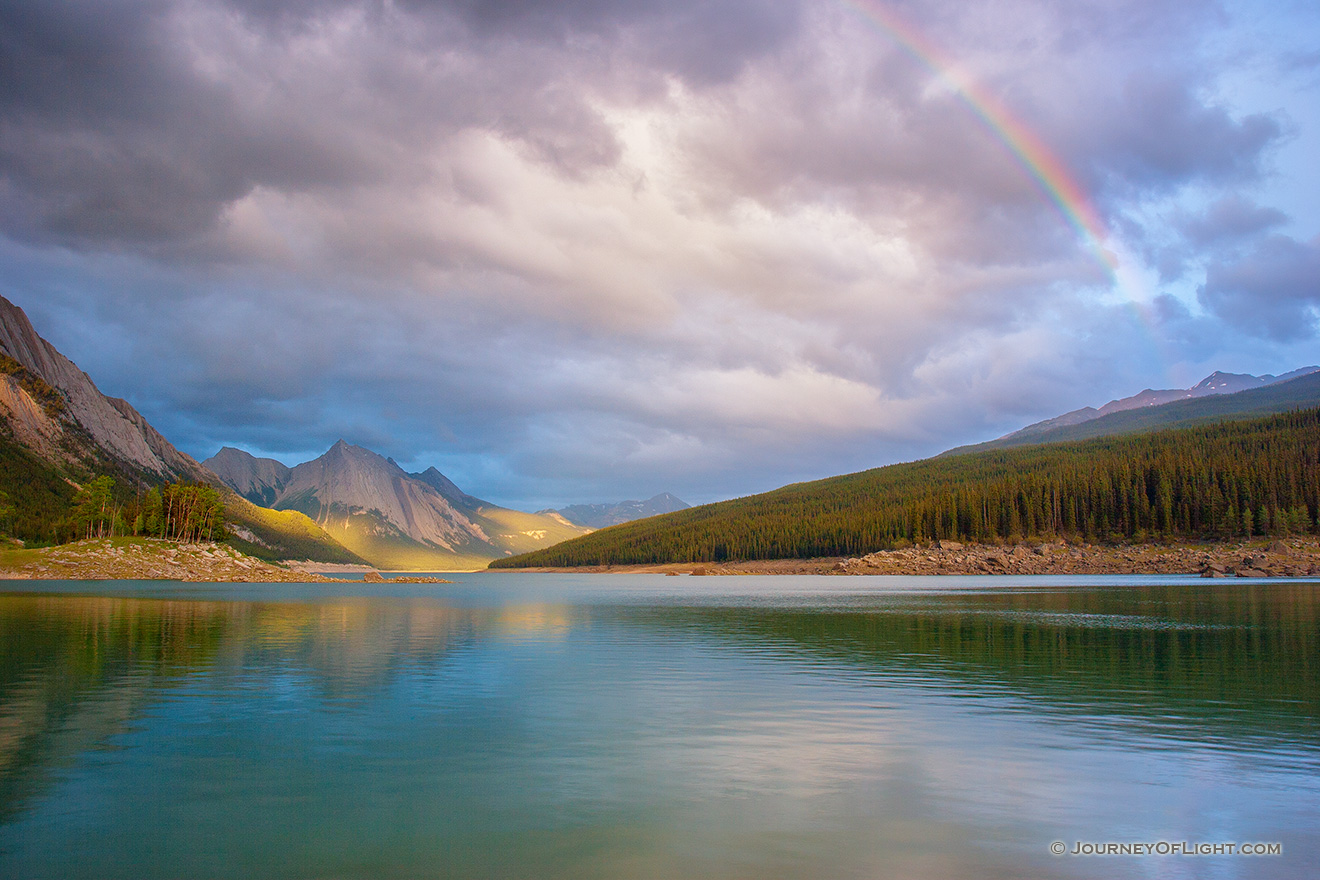 A Rainbow is visible above Medicine Lake in Jasper National Park, Alberta, Canada.  This photograph was captured just as the last rays of the sun peeked through the clouds around 10:30 pm. - Jasper Picture